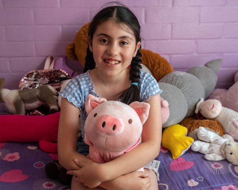 Amelie smiling and holding a plush pig after cleft surgery