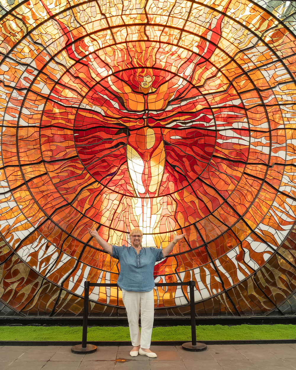 Lidia posing with a stained-glass mural at the Cosmovitral