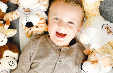 Krista's son surrounded by Cuddles for Clefts stuffed animals with clefts