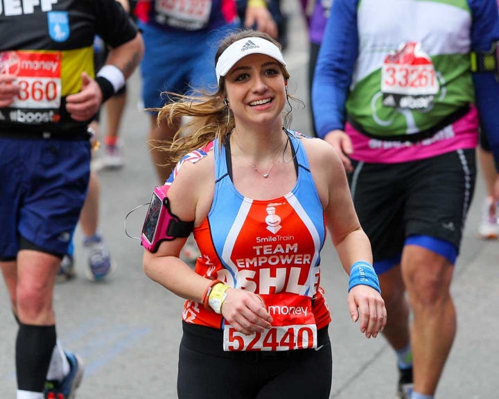 Woman running in marathon with Smile Train kit