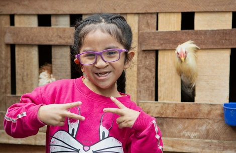 Kristhell flashing two peace signs in front of a chicken coop