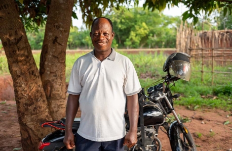 Koli stands in front of his motorcycle and smiles