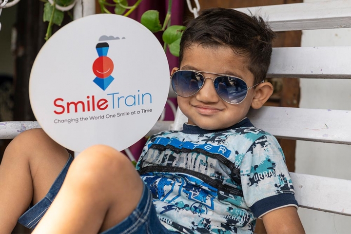 Child wearing sunglasses and Smile Train sign