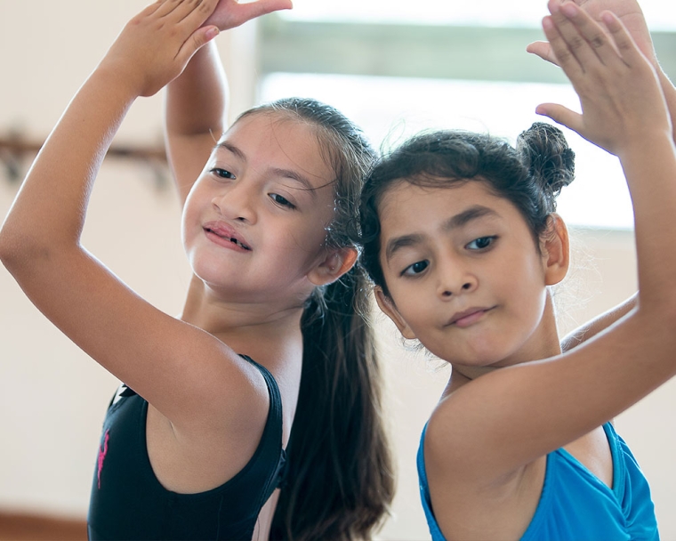 Aquetzaly smiling and doing a ballet move with a friend